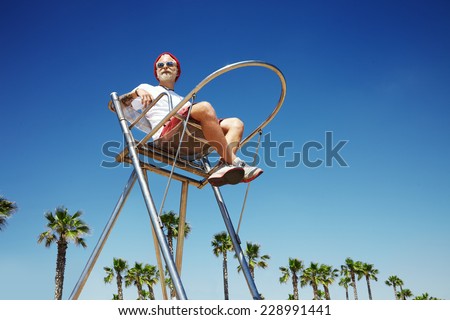 man looking like a young Santa sitting on a lifeguard tower