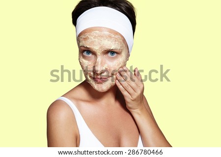 wondering woman making a facial routine on a yellow background