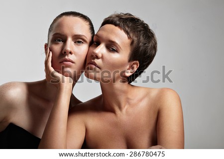 two womn with a different skin type. one of them holding a face of another