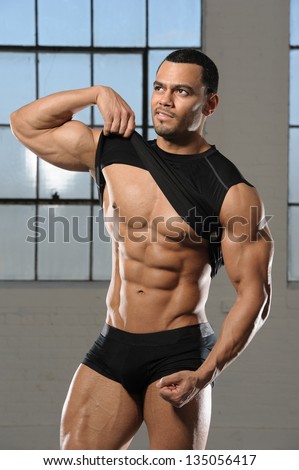 Healthy bodybuilder male with abs lifting shirt up