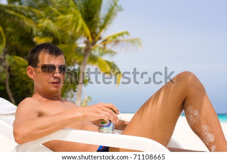 Young man with beer on a tropical beach