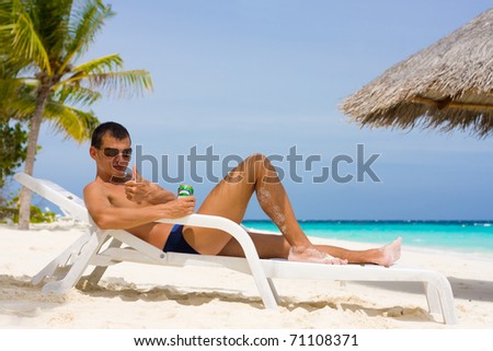Young man with beer on a tropical beach