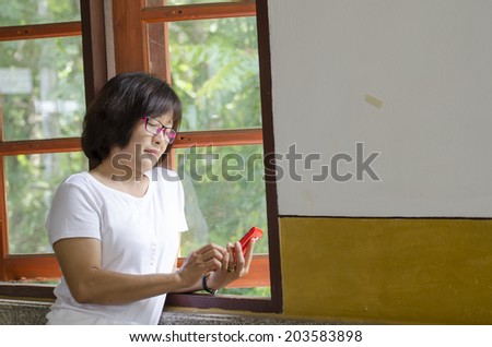 the cute middle aged Asian woman play line with mobile phone