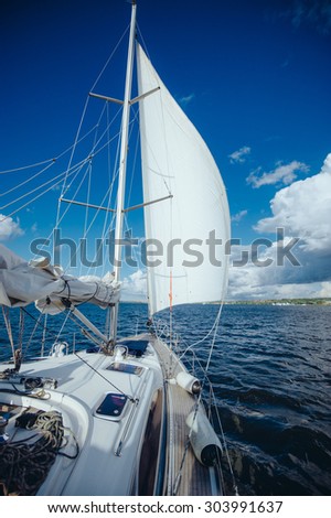 View from the board of a sailing yacht on the waters, sailing ships and the forest growing along the coast, as well as people\'s homes. sailing yacht floating in the wind on a beautiful sunny