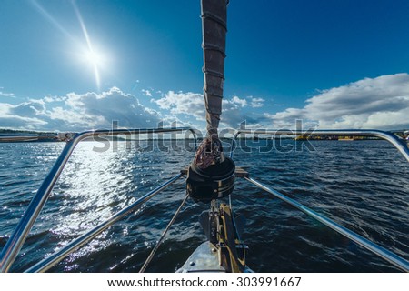 View from the board of a sailing yacht on the waters, sailing ships and the forest growing along the coast, as well as people\'s homes.