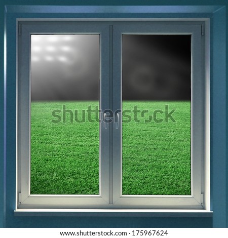 Window view to grass field in night in spotlight