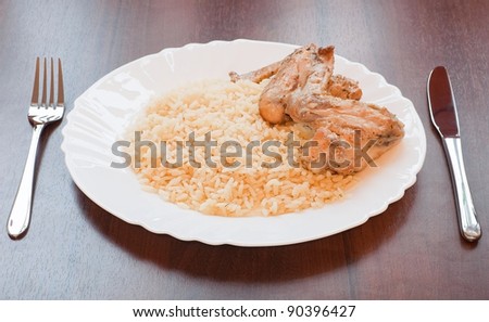 Rice with chicken on plate over wooden table