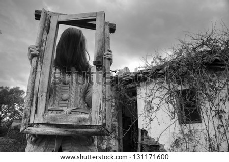 Horror Scene of a scary girl over a spooky abandoned house background