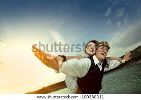 Happy couple enjoying flying over the sea, female on man\'s back