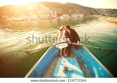 Wedding kiss on the retro boat. Beautiful young couple kissing in a boat with oars.