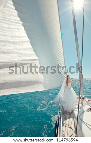 Bride with beautiful golden hair on a yacht with white sails. Wedding at the sea on a yacht.