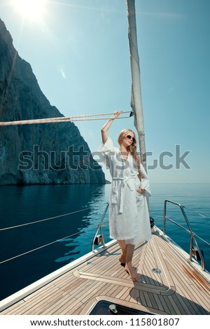 beautiful girl floating in the sea on a boat along the rocky shore