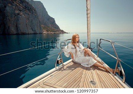 sexy young woman sitting on the yacht in sunglasses and a in dressing gown