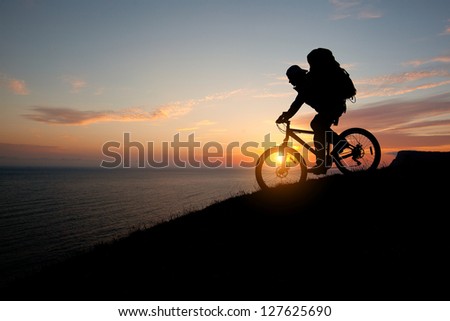 evening silhouette of a man coming down from the tourist mountain bike