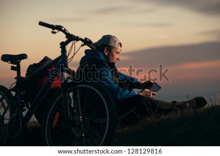 cyclist tourist guy sat down to rest at night with the tablet