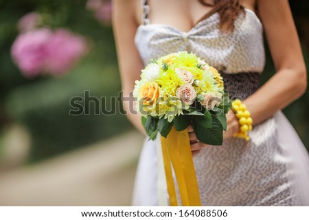 Woman holding wedding flower bouquet of yellow flowers.