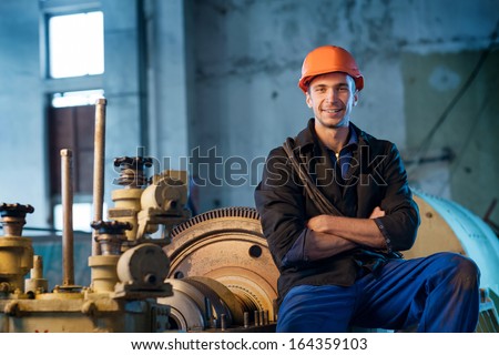 Portrait of a worker in the helmet near the steam turbine