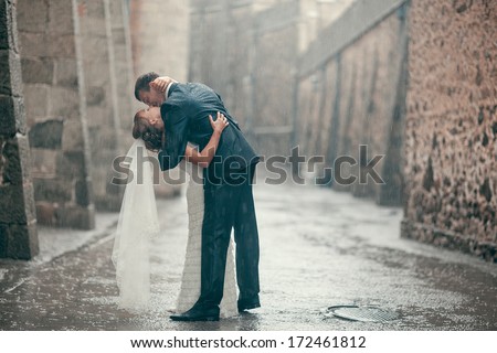 beautiful Wedding couple kissing in the rain