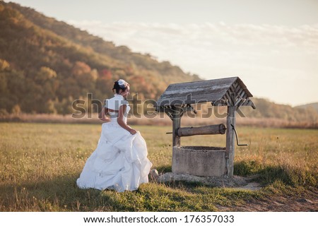 bride in a white wedding dress at the well water.  Wedding rustic theme.