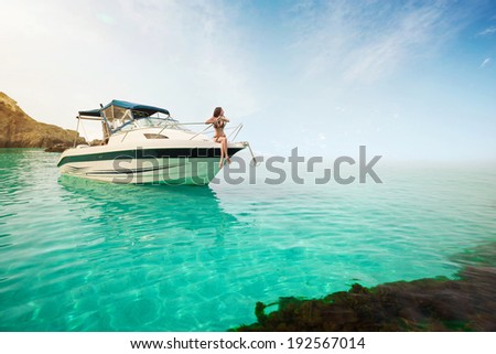 Beautiful young woman sitting on the boat a sunny summer day. Luxury vacation at sea.