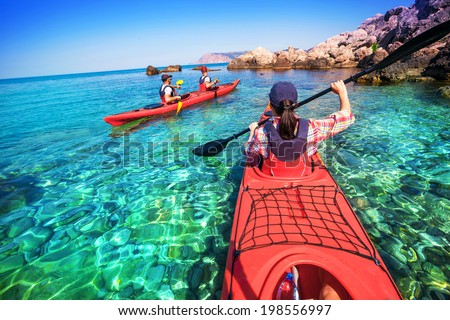 Two men paddle a kayak on the sea. Kayaking on island
