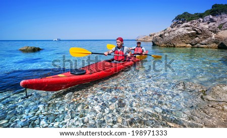 Couple man floating on a sea kayaking on the coast. Traveling by kayak outdoors on a summer day.