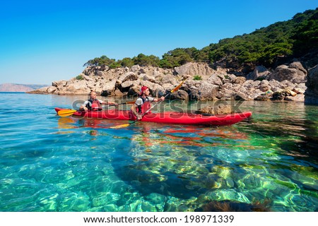 Couple man floating on a sea kayaking on the coast. Traveling by kayak outdoors on a summer day.