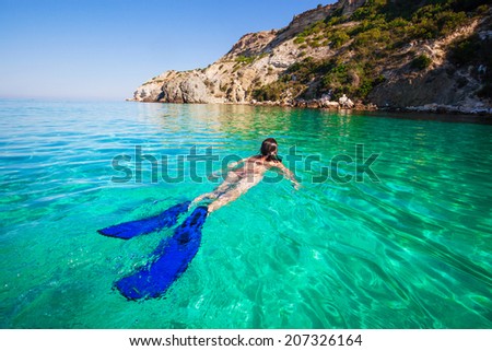 Woman swimming with flippers on the beach. Active holiday in sea.