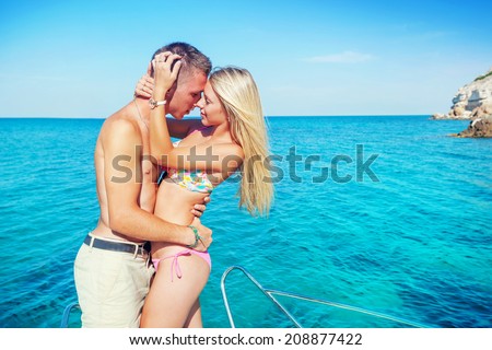 Romantic happy couple in love on a yacht at sea. Man and woman kissing on a boat traveling on the islands. Luxury holidays on the water.