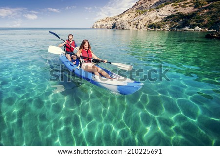 Sailing on the sea kayaking. Young happy couple traveling by kayak. Activities on the water.