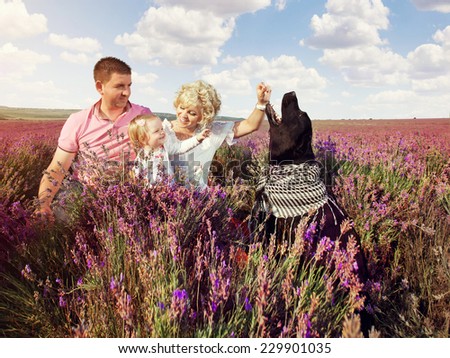 Happy family relaxing in nature lavender field. Mother, father, daughter and dog sitting in the grass.