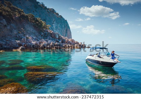 Woman relaxing on a boat in the sea near the rocky shore. Traveling near the island.