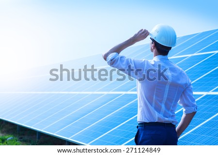 Solar power plant. Man standing near solar panels. Renewable energy.