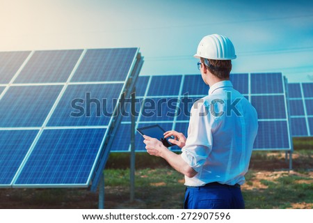 Solar power plant. Engineer with tablet computer on a background of photovoltaic panels. Science solar energy.