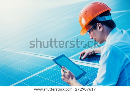 Engineer solar photovoltaic panels station checks with tablet computer.