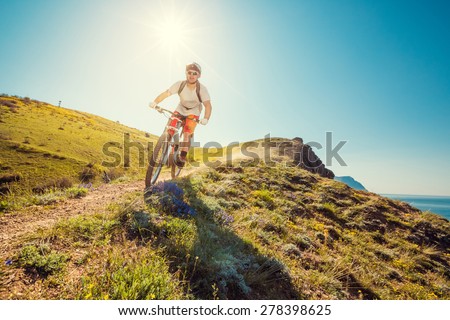 Man on a mountain bike races down the beautiful nature. Downhill