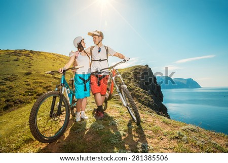 Portrait of a happy couple in the mountains with bicycles. Young man and woman traveling on mountain bikes outdoors.