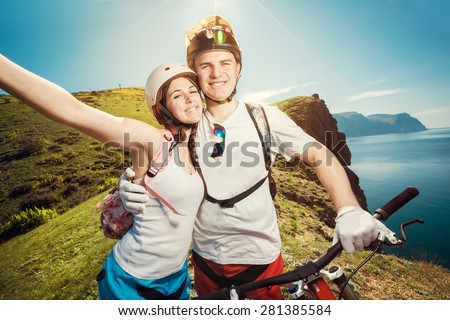 Portrait of a happy couple in the mountains with bicycles. Young man and woman traveling on mountain bikes outdoors.