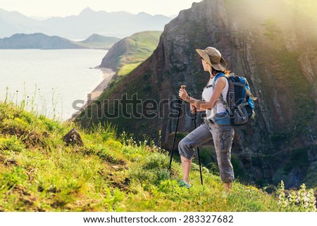 Woman hiking. Hike in the mountains. Woman traveler with backpack on beautiful summer landscape.