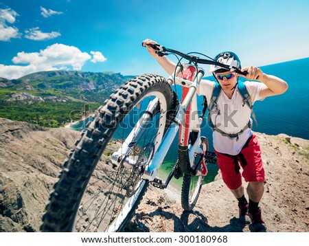 Man pushing a mountain bike up the hill. Adventure travel on bicycle.