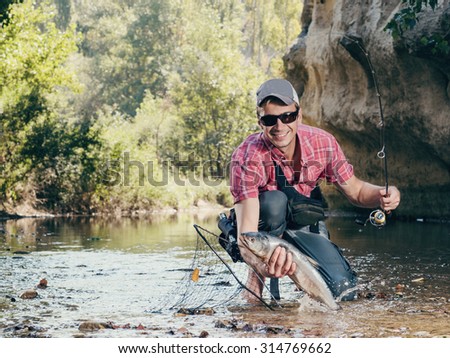 Fisherman. Fishing on the river fly fishing. Man fisherman holds in hand large catch fish.