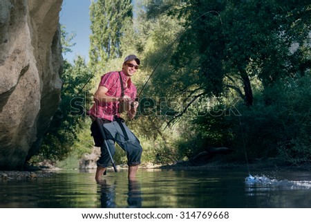 Fishing on the river. Professional sports fisherman  catches a fish.