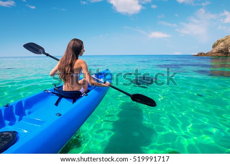 Beautiful young woman kayaking in the sea near the islands. Adventure by kayak.