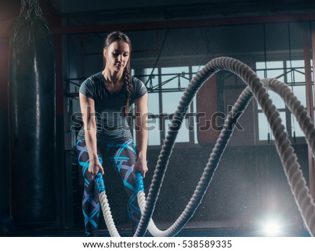 Woman with battle rope battle ropes exercise in the fitness gym. CrossFit.