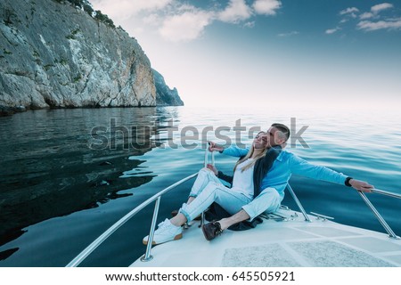 Young Couple Relaxing on a Yacht. Happy wealthy man and a woman by private boat have sea trip.