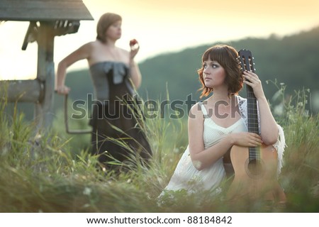 Portrait  two young women on the nature of the guitar at the well
