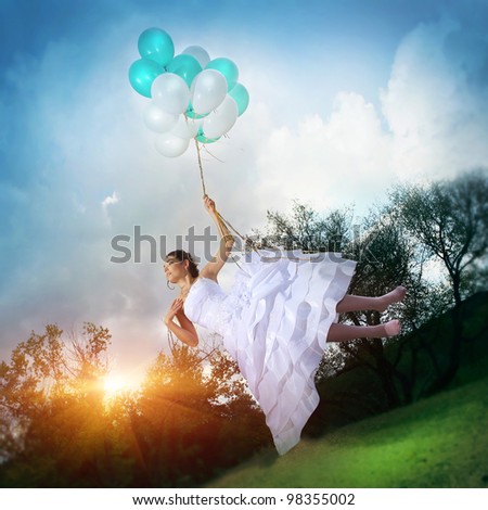Beautiful girl in a wedding dress flying on balloons