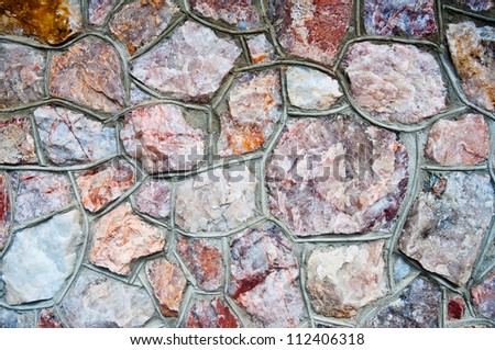 Natural stone wall background. Close-up texture detail. Rust, pink, brown, mauve shades of quartz rock.