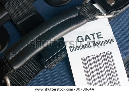 Close up of airline checked baggage label on blue suitcase. Attached at the departure gate to carry on luggage that is too big for aircraft cabin. Horizontal view.