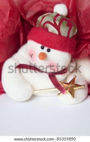 Red and white holiday background. Jaunty toy snowman on white box with red tissue paper.